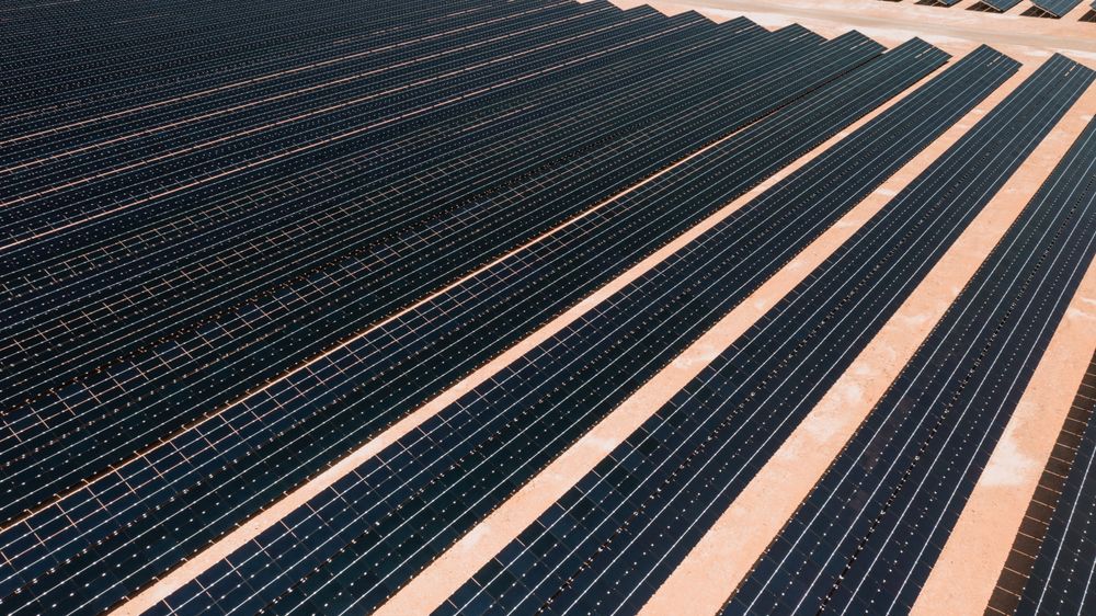 Dark solar panel rows converging in diagonal lines across a solar farm