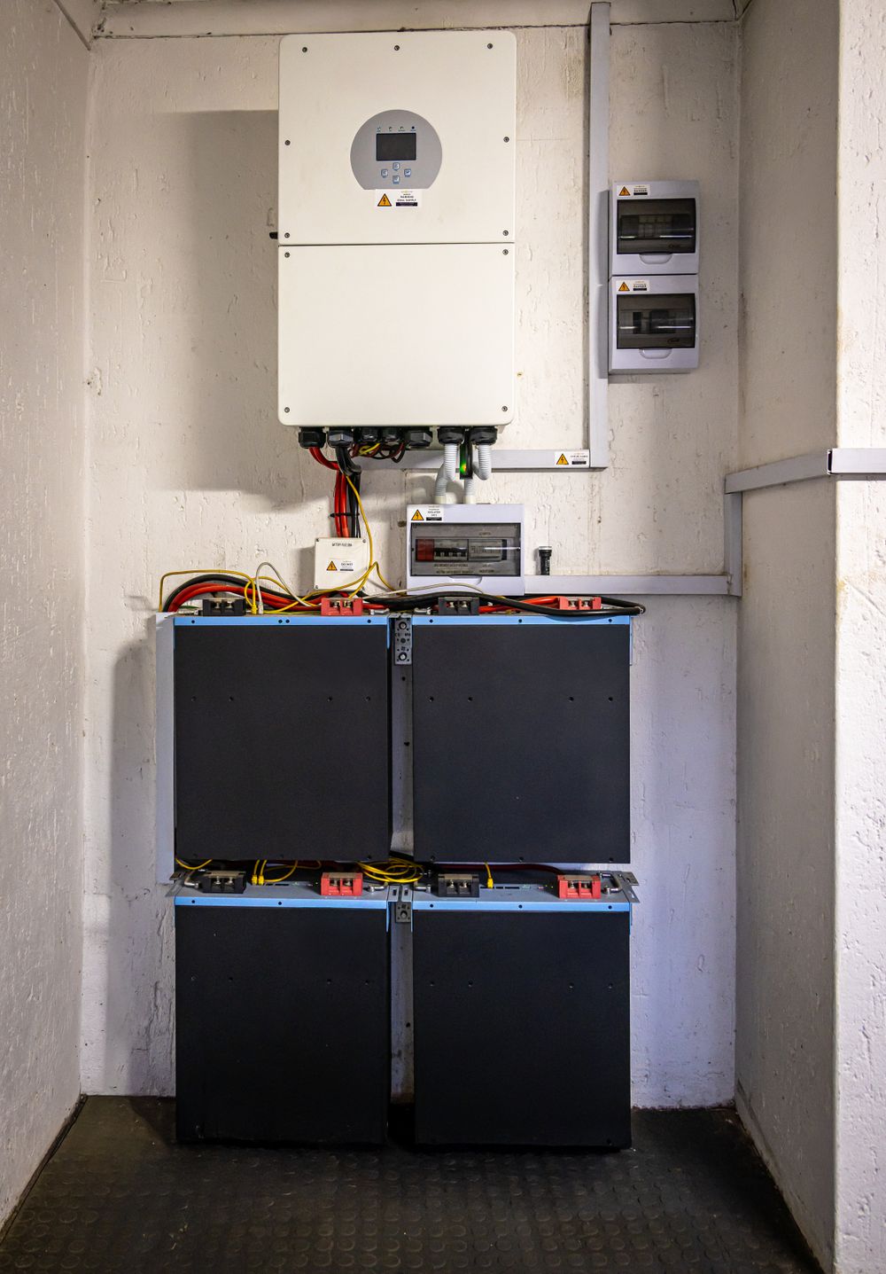 A battery storage bank wired beneath a wall-mounted inverter unit