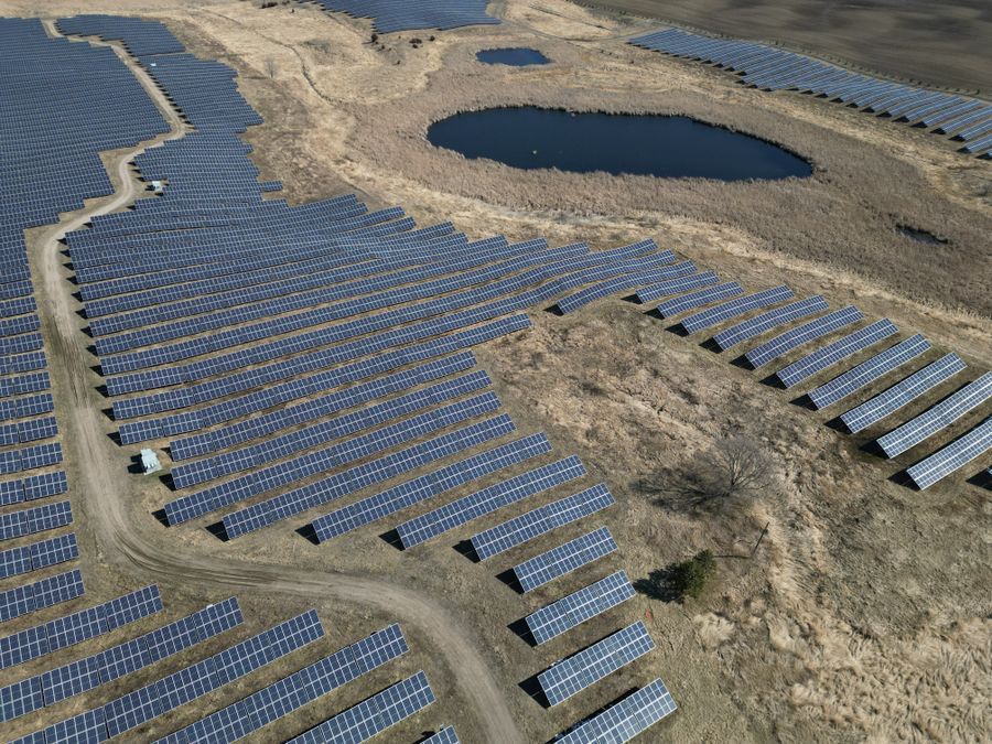 Aerial view of a large solar farm curving around a pond